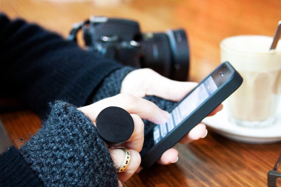 Hand holding a phone beside a coffee cup, checking a new message