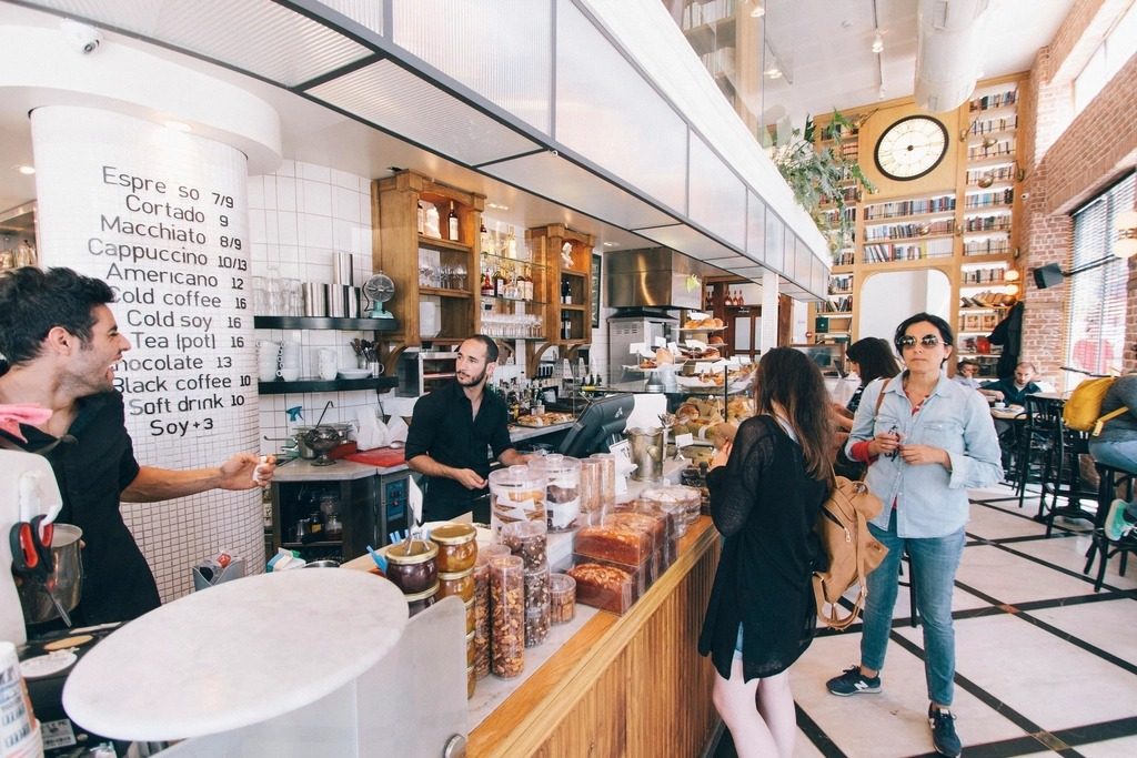 Staff serving customers at the counter of a busy neighborhood cafe