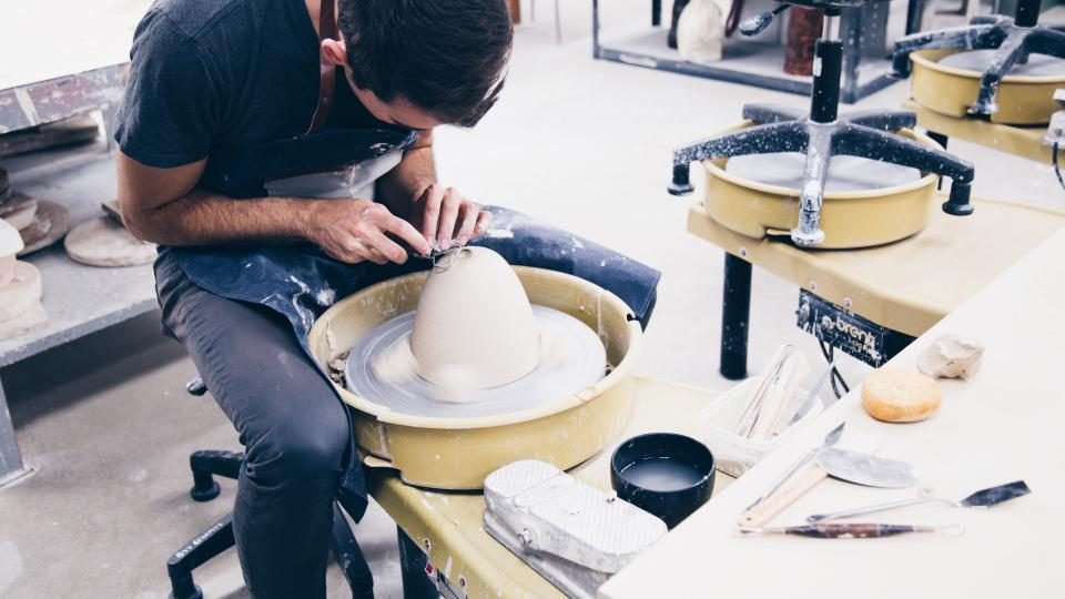 Small-business owner shaping a bowl on a pottery wheel in their studio